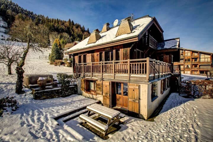 Chalet exterior with wrap-around balcony, hot tub, and outdoor picnic area