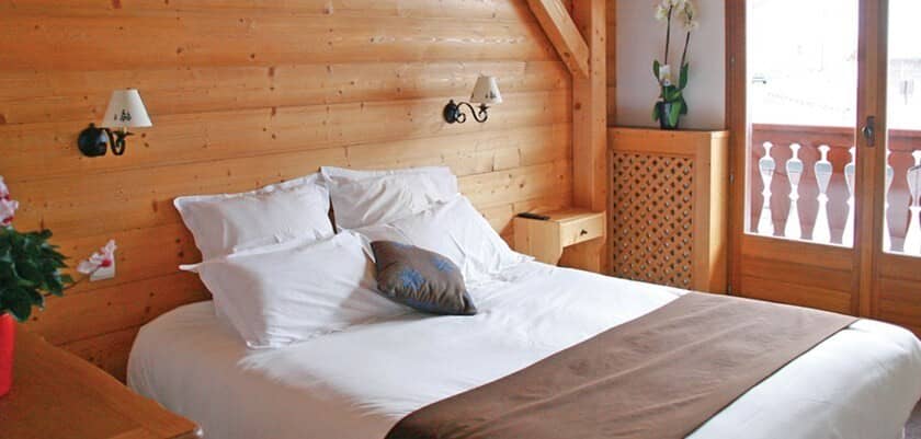 Bedroom with wood-paneled walls and direct balcony access