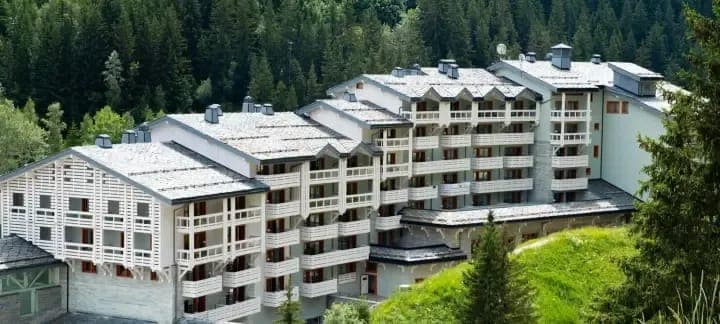 Resort exterior with private balconies and surrounding pine forest
