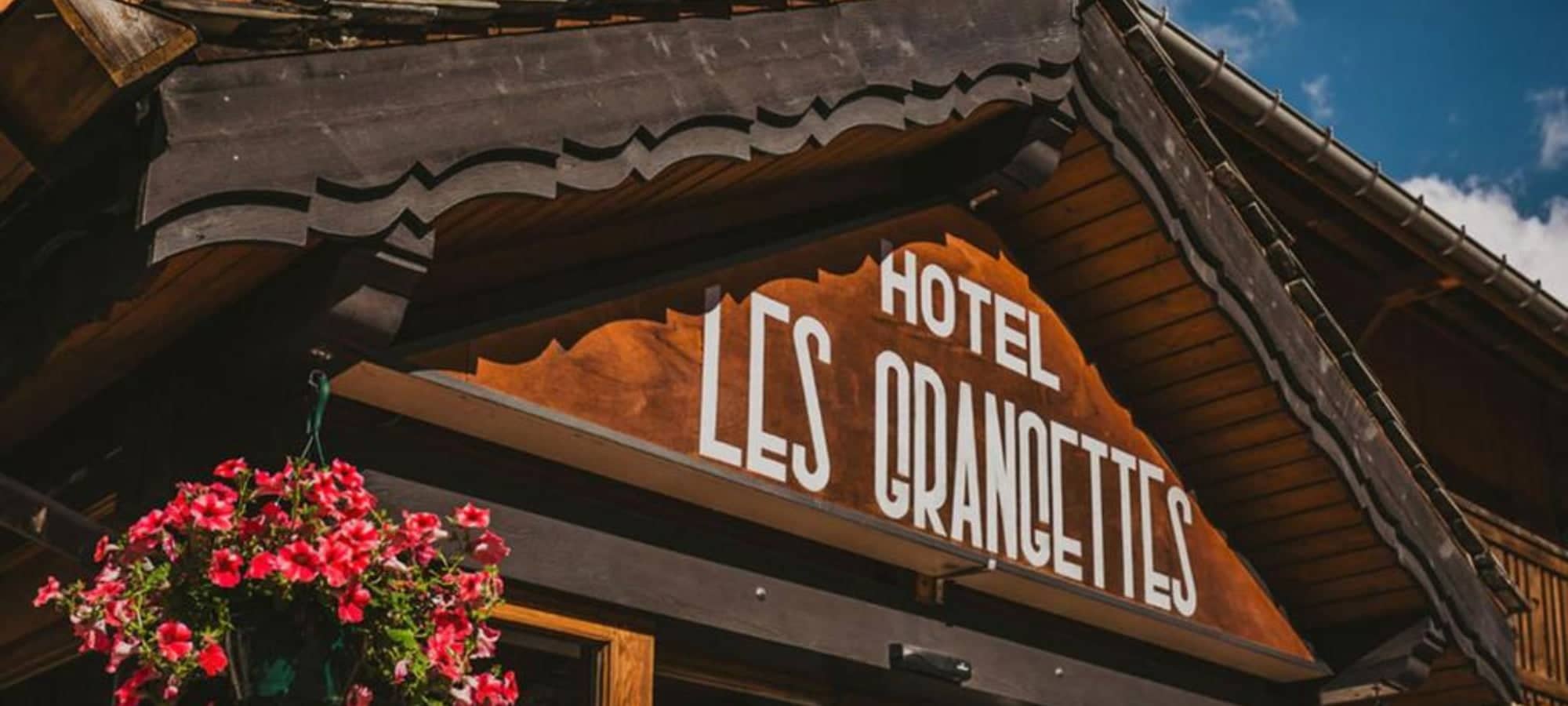Hotel Les Grancettes entrance with traditional wood carving and floral displays