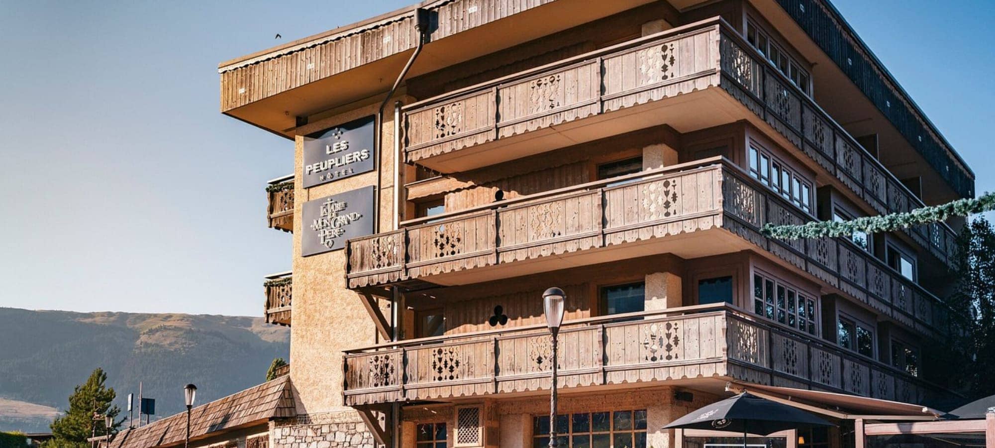 Hotel exterior with private wooden balconies and ground floor patio seating