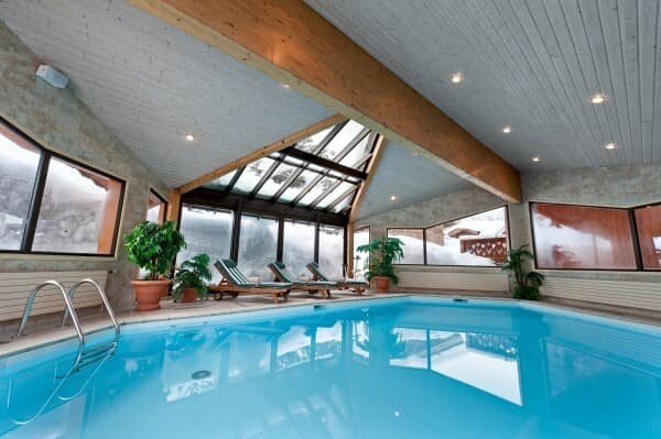 Indoor pool with glass atrium and poolside lounge seating