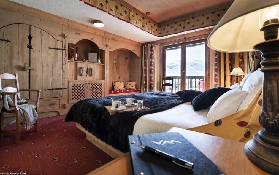 Bedroom with king bed and balcony offering snowy mountain views
