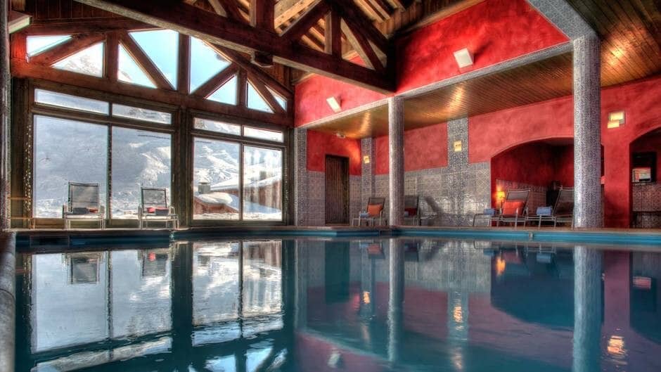 Indoor pool with vaulted timber ceiling and snowy mountain views