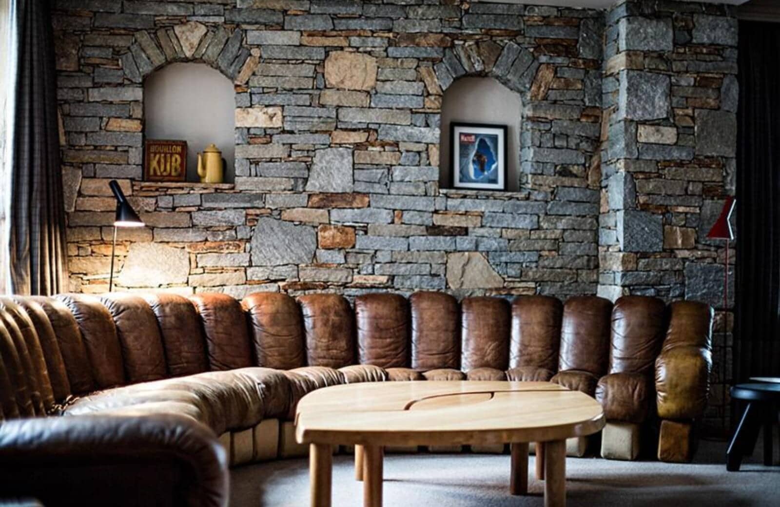Living area with curved leather sectional and exposed stone wall