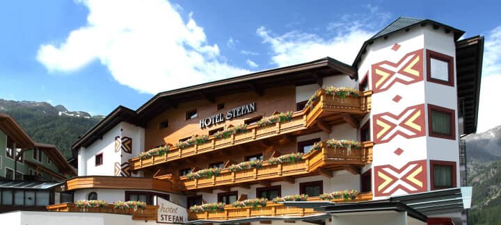 Hotel exterior featuring timber balconies with flower boxes and mountain backdrop