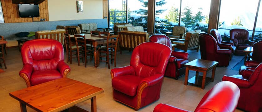 Shared lounge area with leather armchairs and floor-to-ceiling mountain views