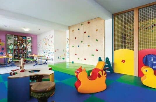 Children's playroom with indoor climbing wall, safety mats, and craft stations