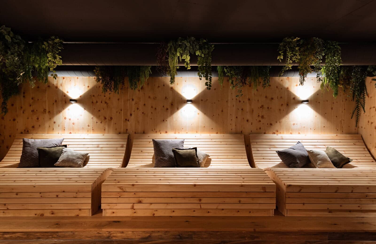 Spa relaxation room with three oversized wooden daybeds and ambient lighting
