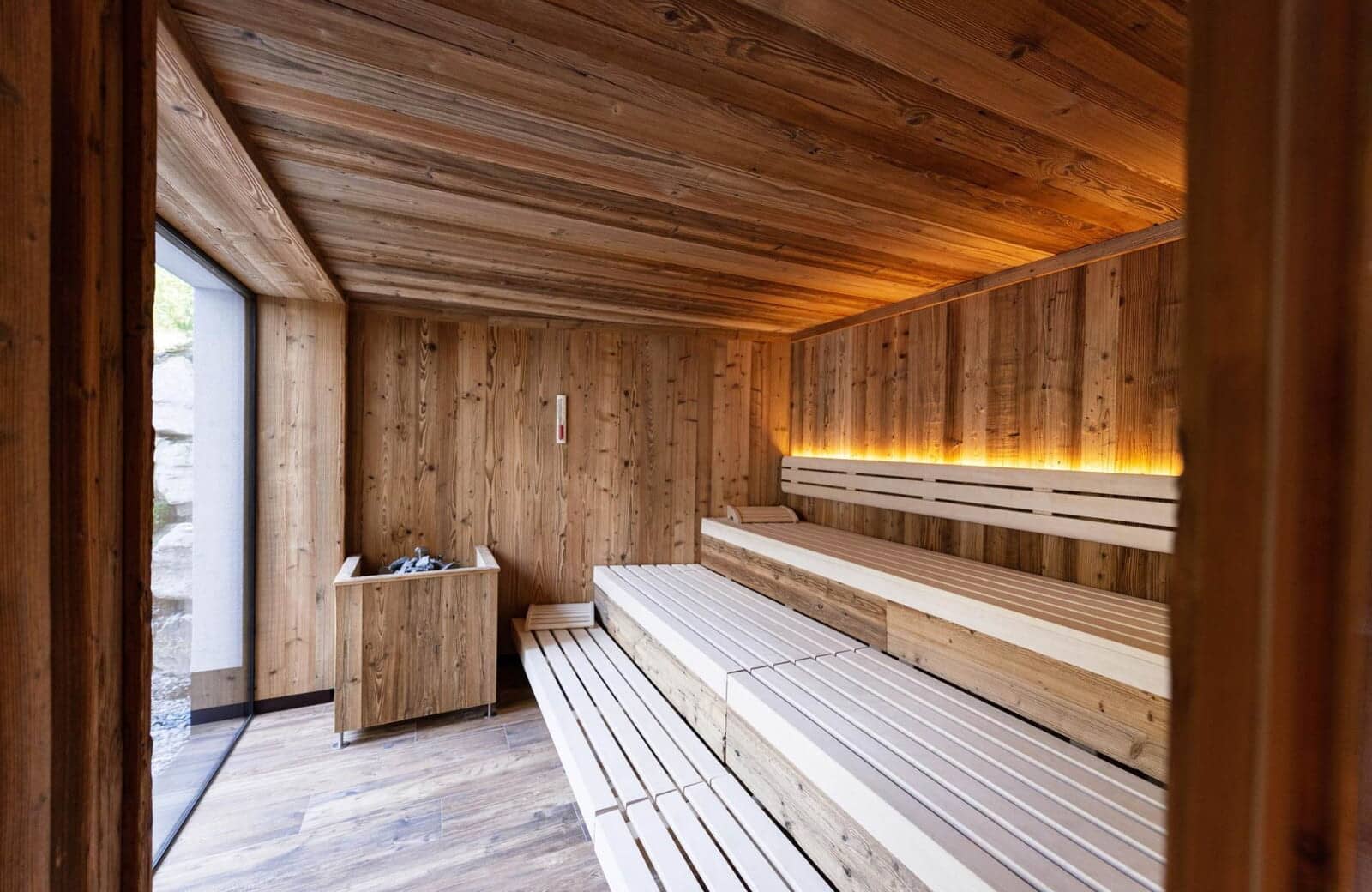 Wood-paneled sauna with multi-level seating and floor-to-ceiling window