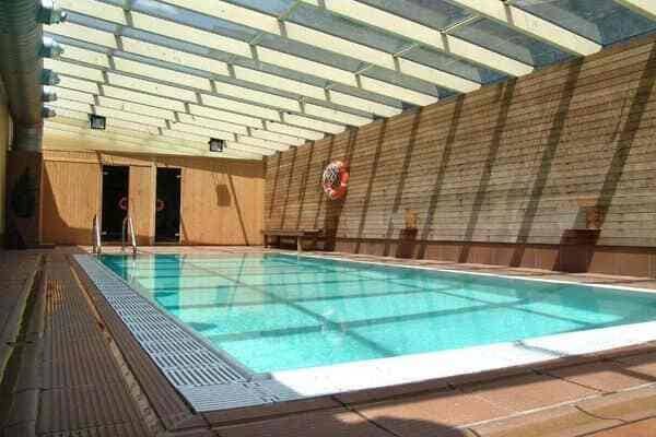 Indoor heated pool with retractable glass roof and wood-paneled walls