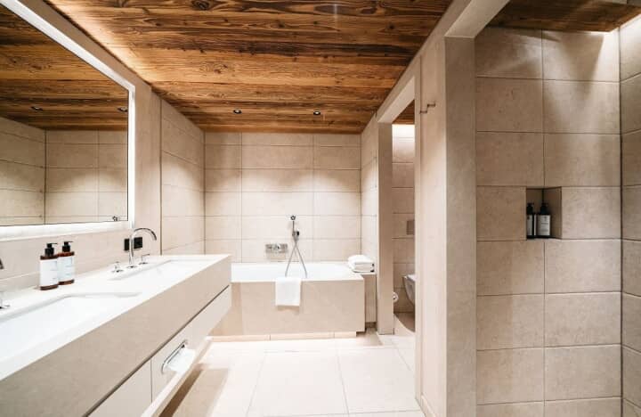 Bathroom with dual vanity, soaking tub, and reclaimed wood ceiling