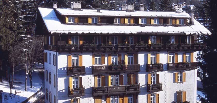 Chalet exterior with private balconies and snow-covered roof near forest