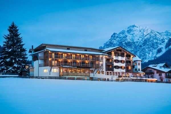 Ski-in lodge exterior with private balconies and mountain peak backdrop