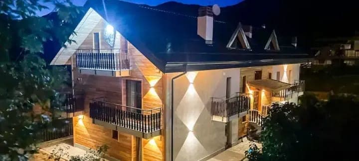 Chalet exterior at night with multiple private balconies and mountain backdrop