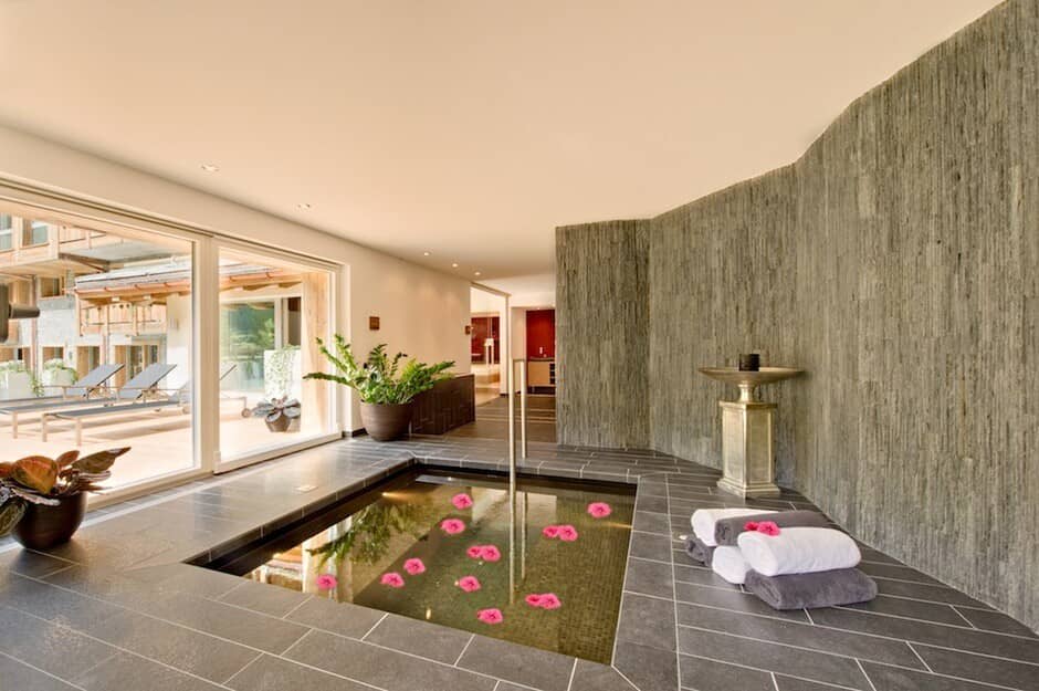 Indoor spa pool with textured stone walls and terrace access