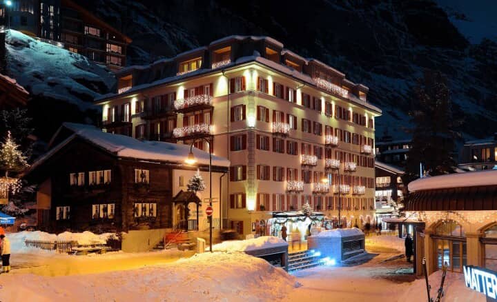 Hotel exterior at night with illuminated balconies and snow-covered pedestrian access