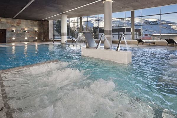 Indoor pool with massage jets and floor-to-ceiling mountain views