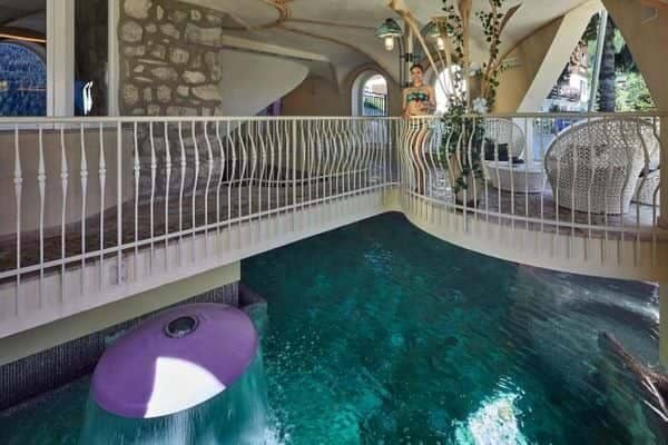 Indoor grotto pool with waterfall feature and overhead mezzanine lounge