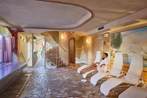 Spa lounge with heated tile floors, reclining chairs, and spiral staircase access