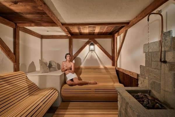 Indoor sauna with curved timber seating and traditional stone heater