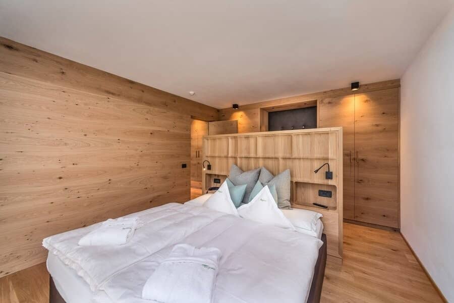 Primary bedroom with oak paneling, integrated reading lights, and built-in wardrobes