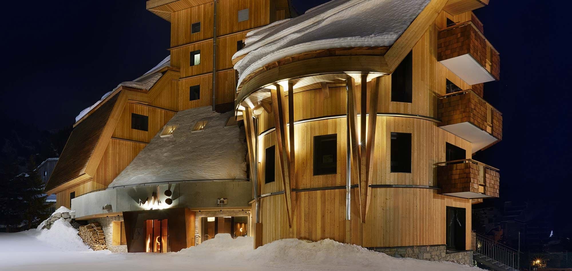 Cedar-clad lodge exterior with private balconies and curved architecture