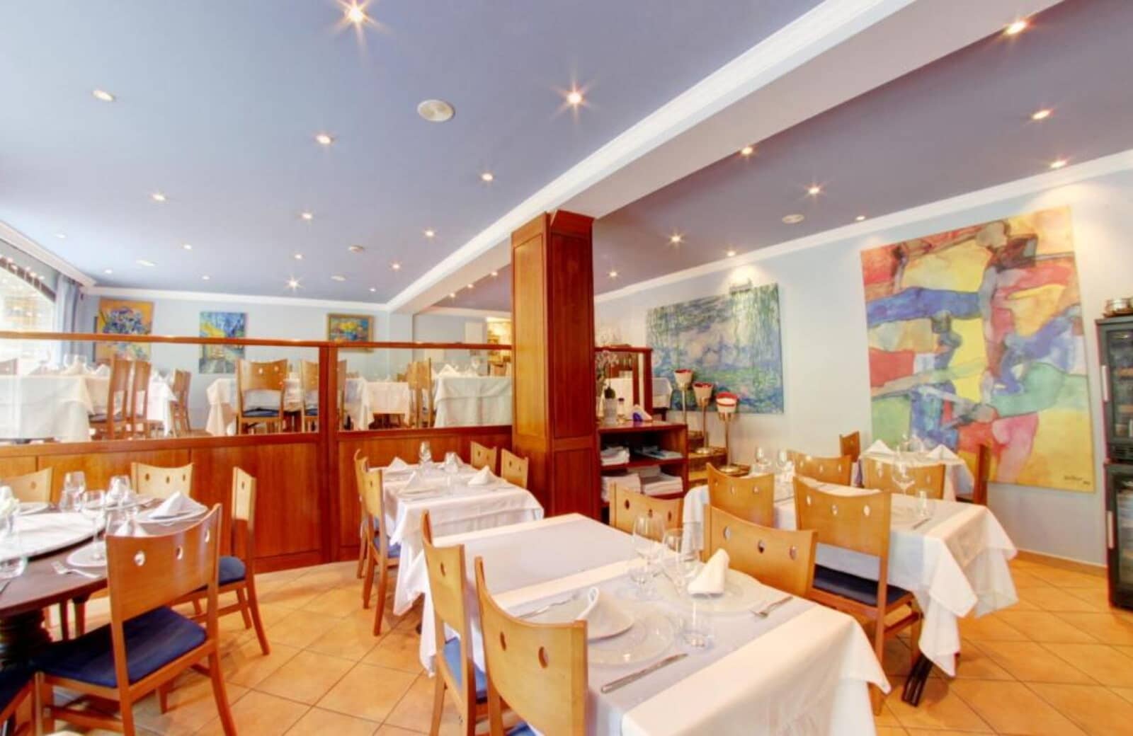 Dining area with white-linen tables and recessed ceiling lighting