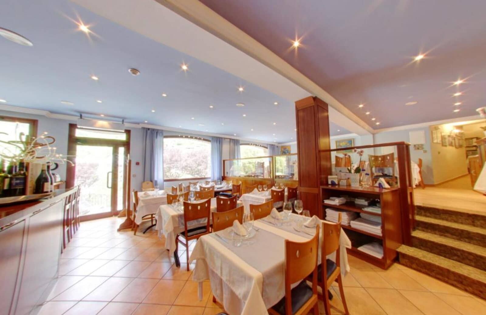 Dining room with white linens, bar seating, and outdoor terrace access