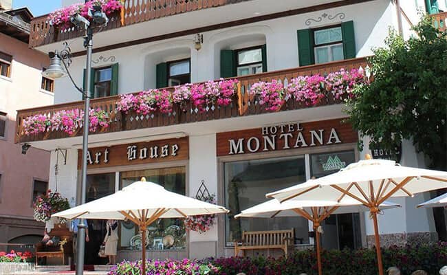 Hotel facade with flower-lined balconies and outdoor cafe seating