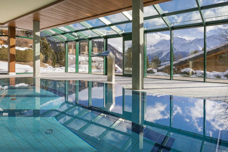 Indoor pool with glass atrium and mountain views