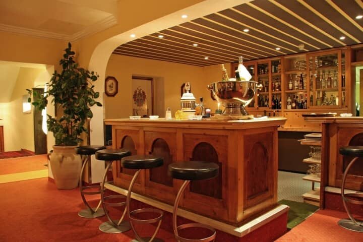 Lower-level wet bar with wood paneling and stool seating for five