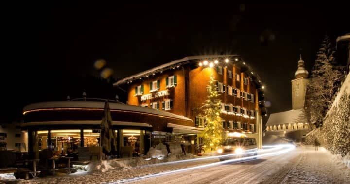 Hotel exterior at night with street-level restaurant and nearby village church