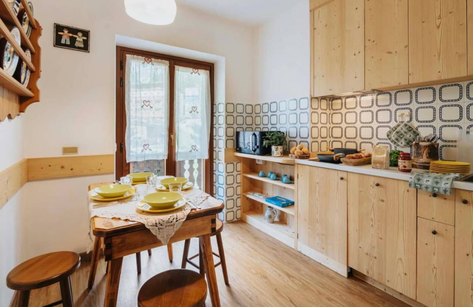Eat-in kitchen with patterned tile backsplash and wooden dining table for four