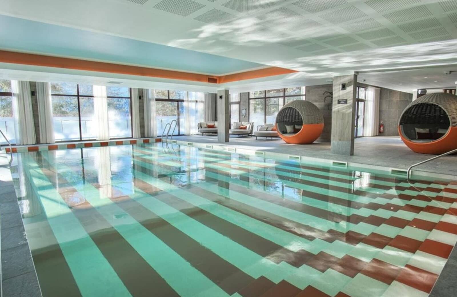 Indoor pool with spherical daybeds and snowy mountain views