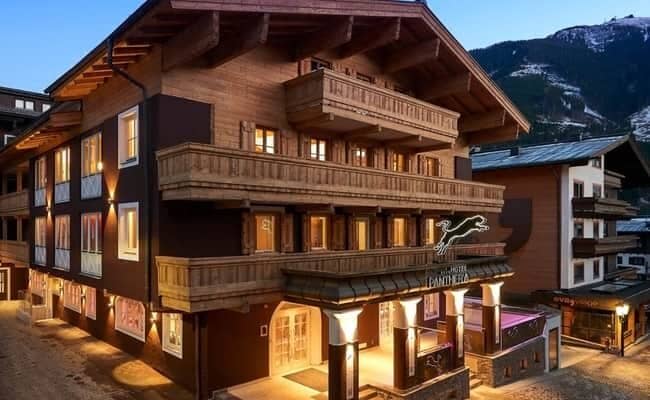 Chalet exterior featuring private balconies and illuminated entryway near mountain slopes