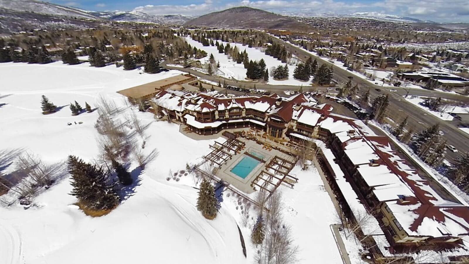 Aerial view of lodge with heated outdoor pool and nearby golf course