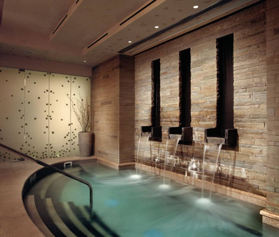 Indoor heated grotto pool with stone water features and step entry