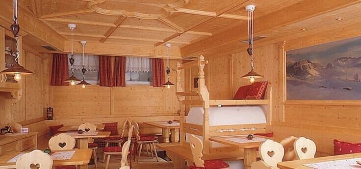 Traditional alpine dining area featuring carved wood paneling and masonry stove heater