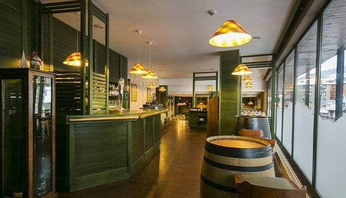 Bar area with green paneled counter and barrel-style tables