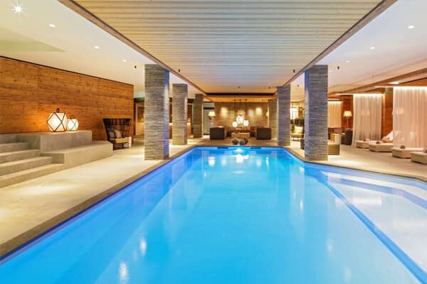 Indoor heated pool with poolside lounge seating and integrated stone steps