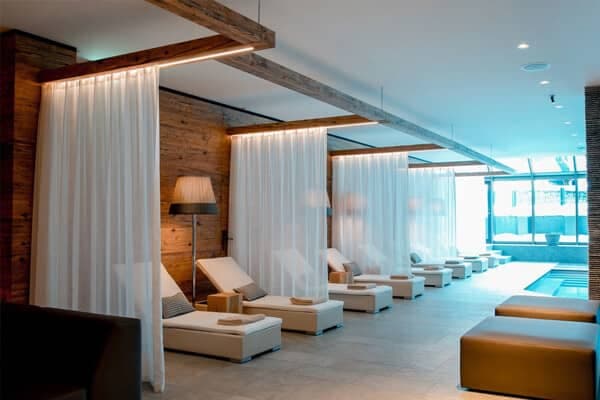 Indoor pool lounge with private curtained daybeds and integrated reading lights