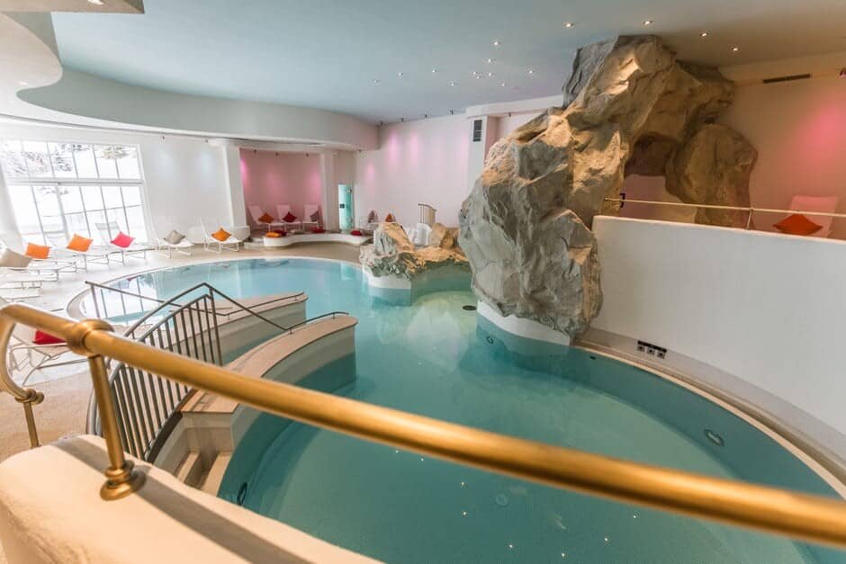 Indoor pool with grotto-style rock feature and poolside loungers