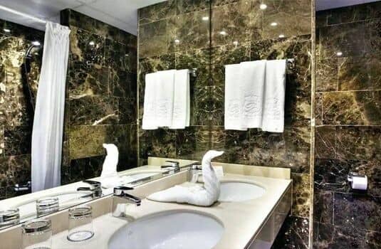 Bathroom with dual vanity, marble tiling, and walk-in shower