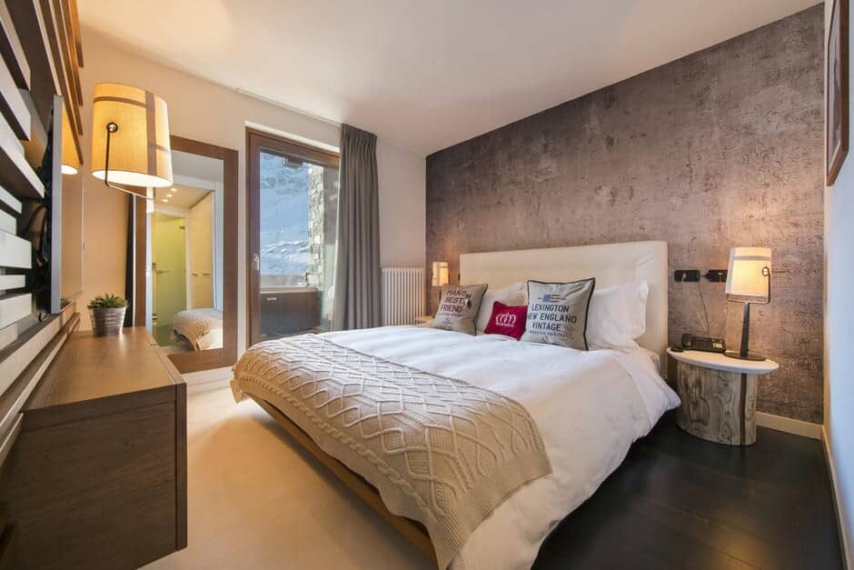 Bedroom with king bed and balcony overlooking snowy mountains