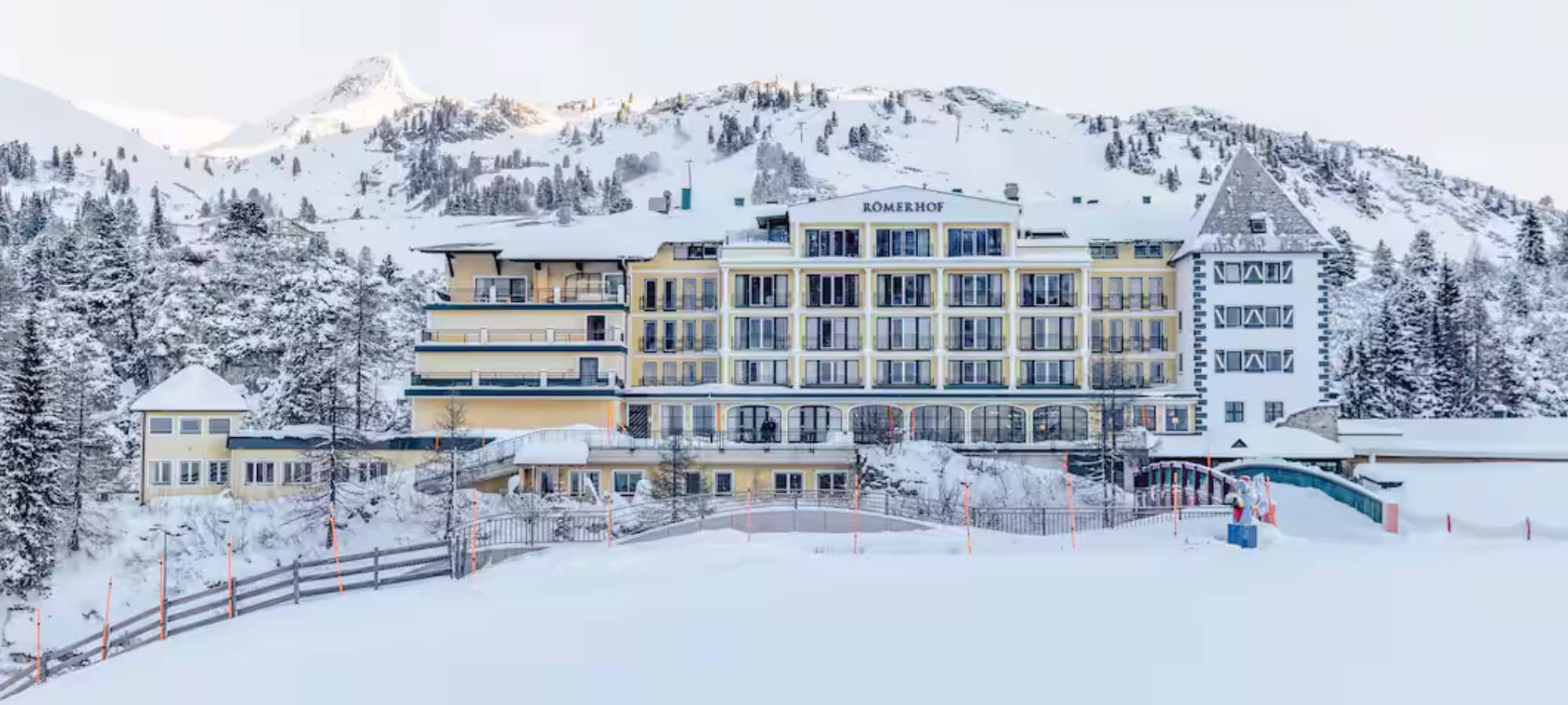 Ski-in/ski-out hotel exterior with mountain backdrop and private balconies