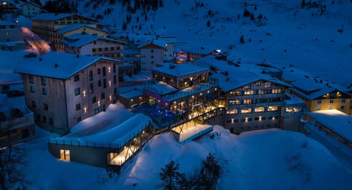 Ski-in/ski-out resort exterior with heated outdoor pool and terrace lighting