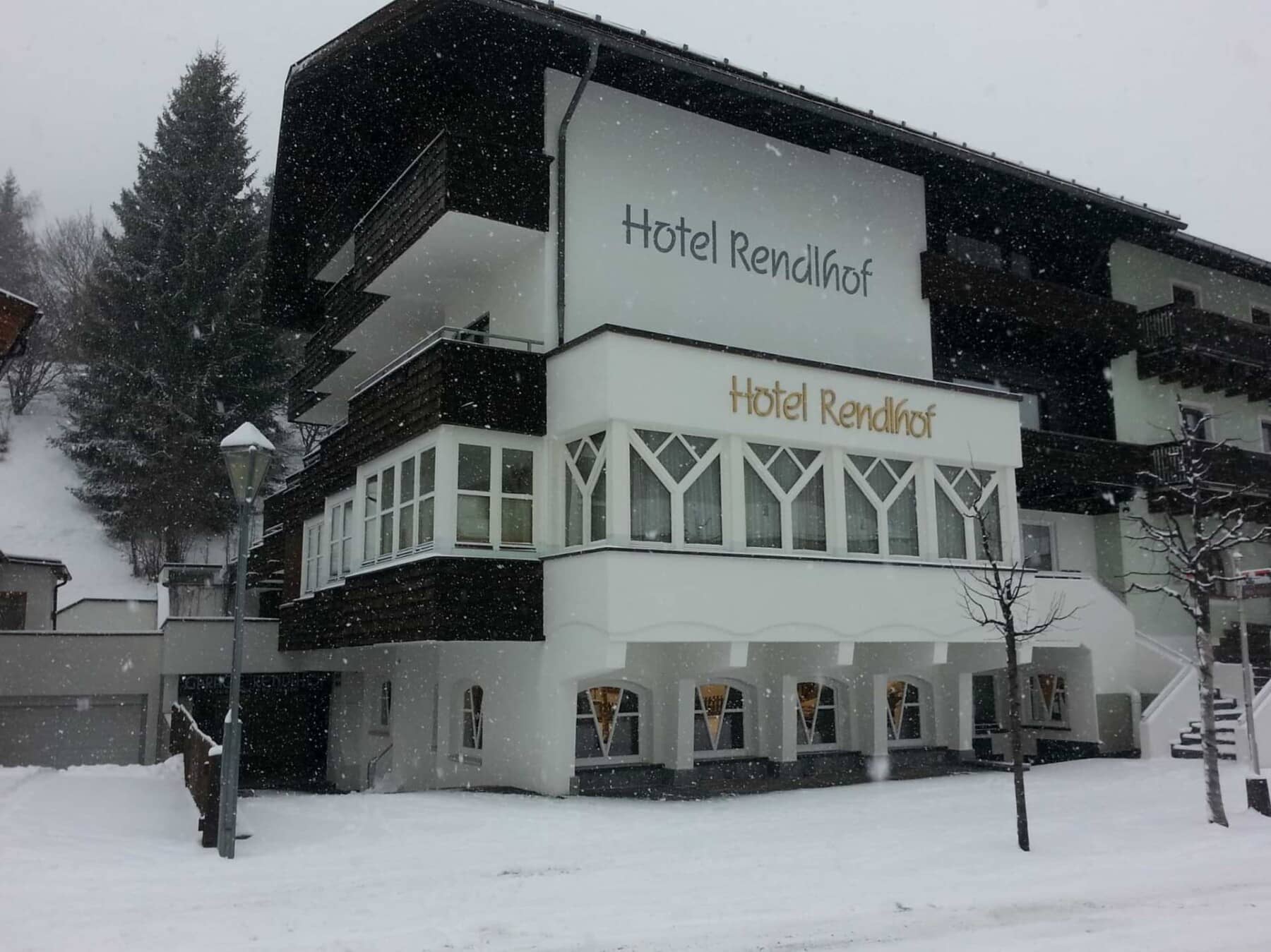 Hotel exterior with private balconies and street-level access during winter snow