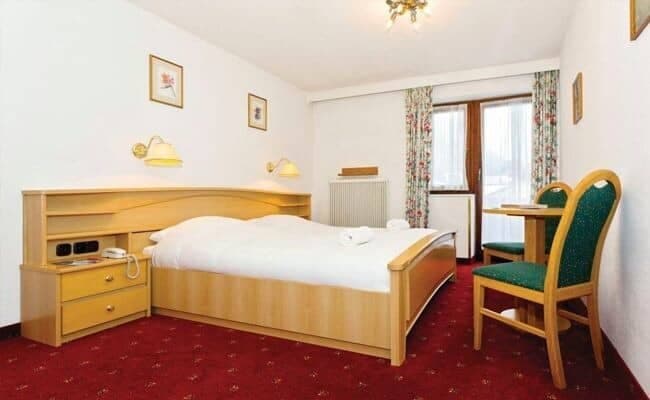 Guest bedroom with double bed, built-in shelving, and cafe seating for two