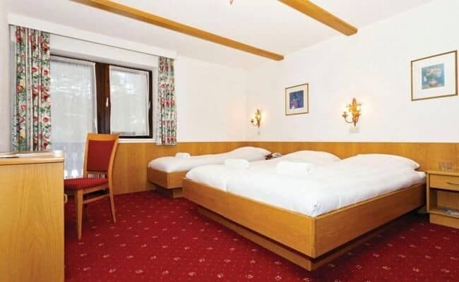 Guest bedroom with triple bed setup and dedicated desk workspace